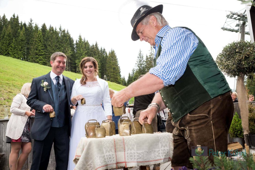 Brautpaar feiert mit traditioneller Zeremonie im Salzburgerland, im Hintergrund Natur.