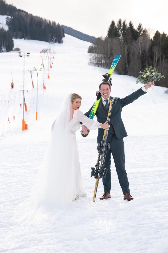 Brautpaar im Schnee mit Skiern, symbolisiert eine winterliche Hochzeit im Salzburgerland.